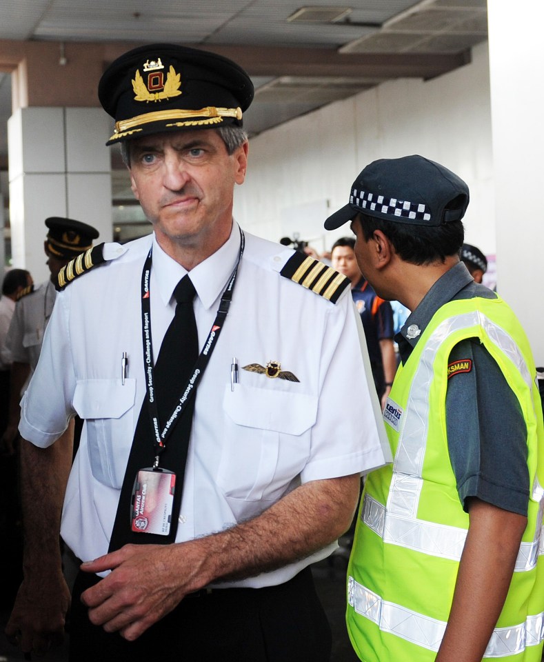 a pilot has a lanyard around his neck that says ' singapore airlines ' on it