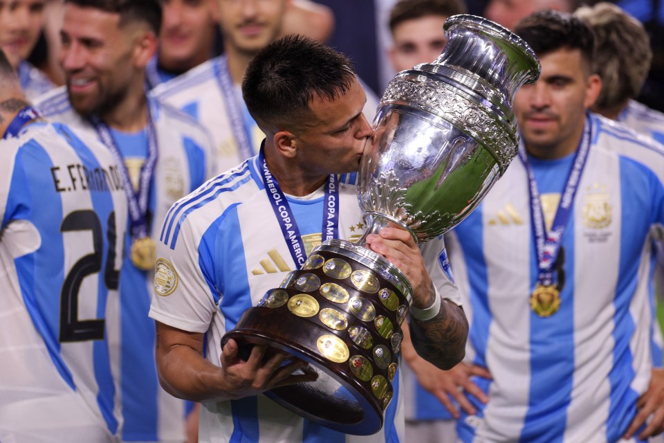 a soccer player kisses a trophy that says copa america on it