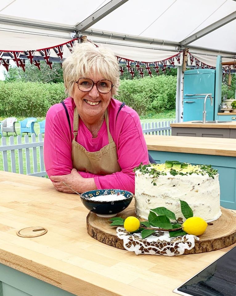 a woman leans on a counter next to a cake