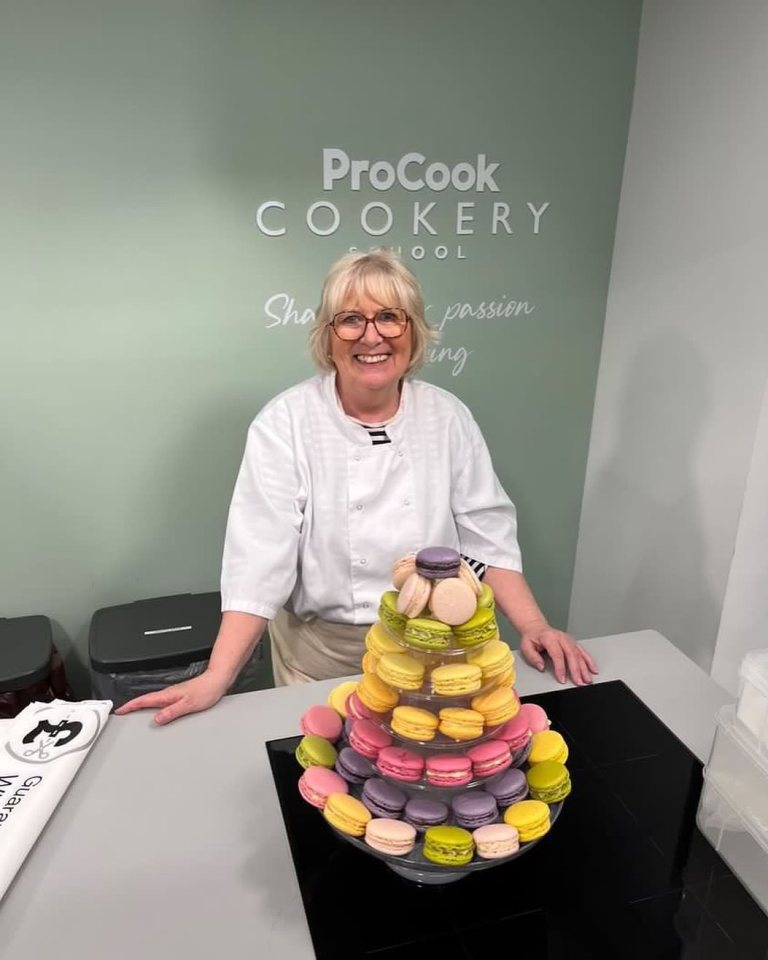 a woman stands in front of a procook cookery sign