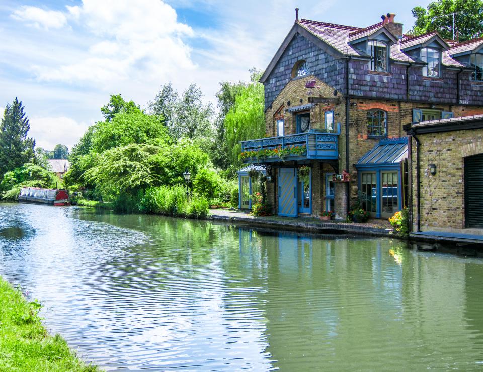 a house with a blue balcony sits next to a river