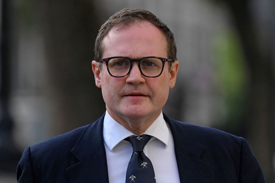 a man wearing glasses and a tie looks at the camera