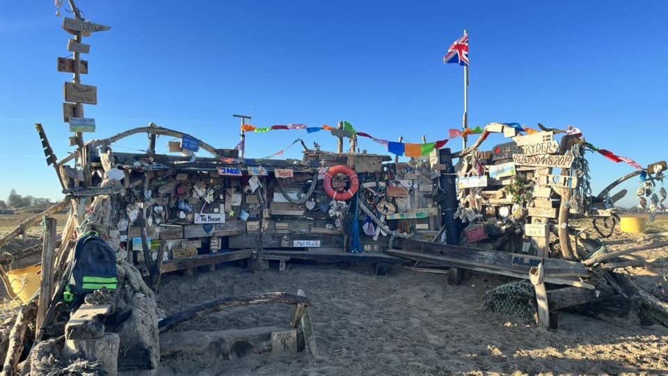 This quirky little community art project is made up of driftwood, flags and mementoes