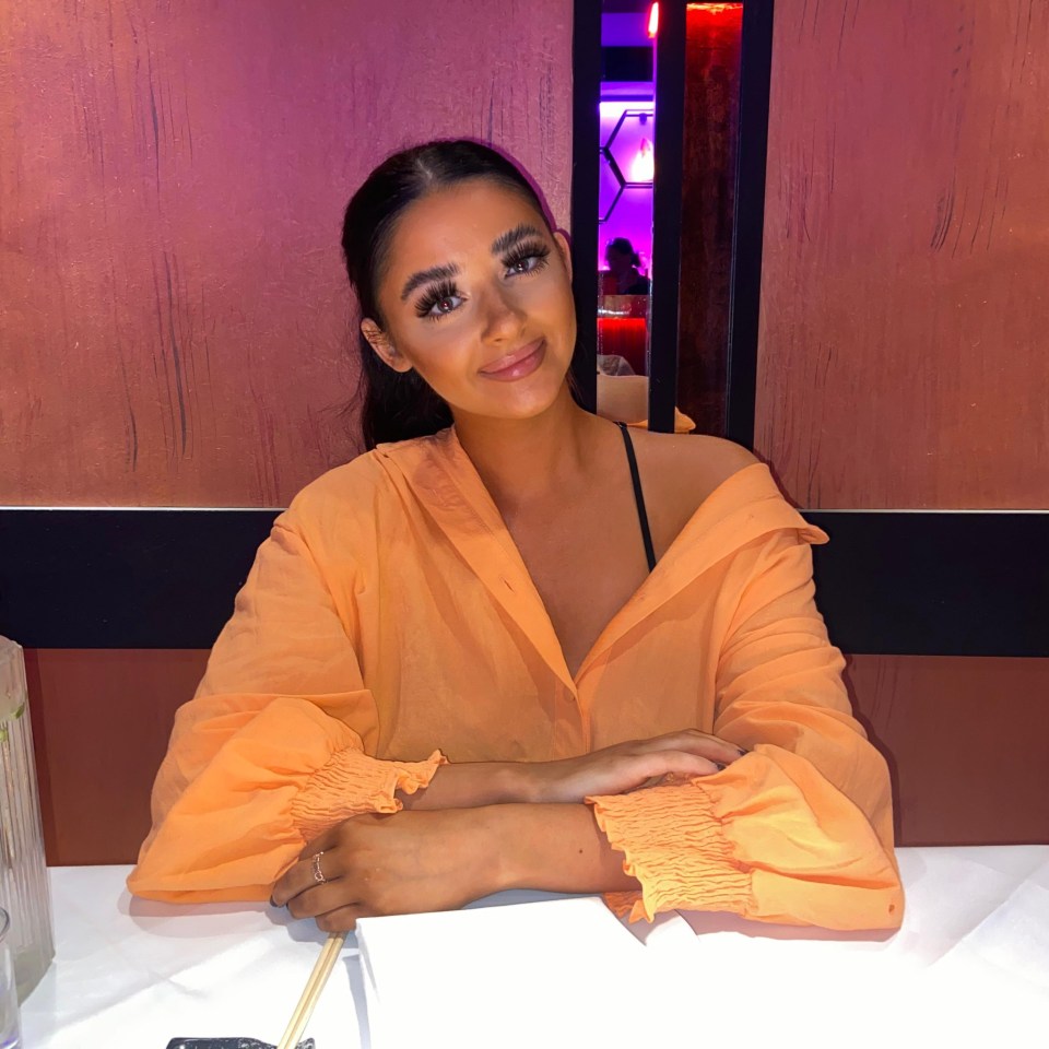 a woman in an orange shirt sits at a table with chopsticks