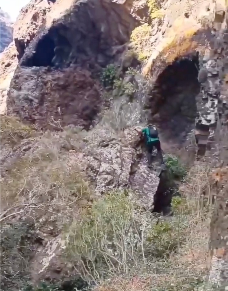 a person with a backpack is climbing up a rocky cliff