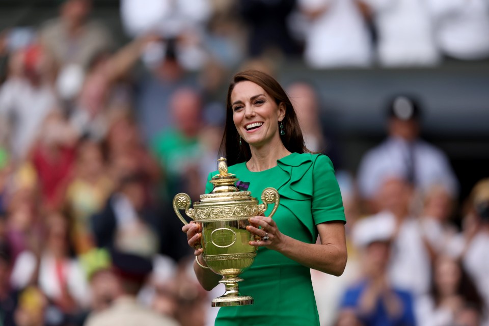 a woman in a green dress is holding a trophy