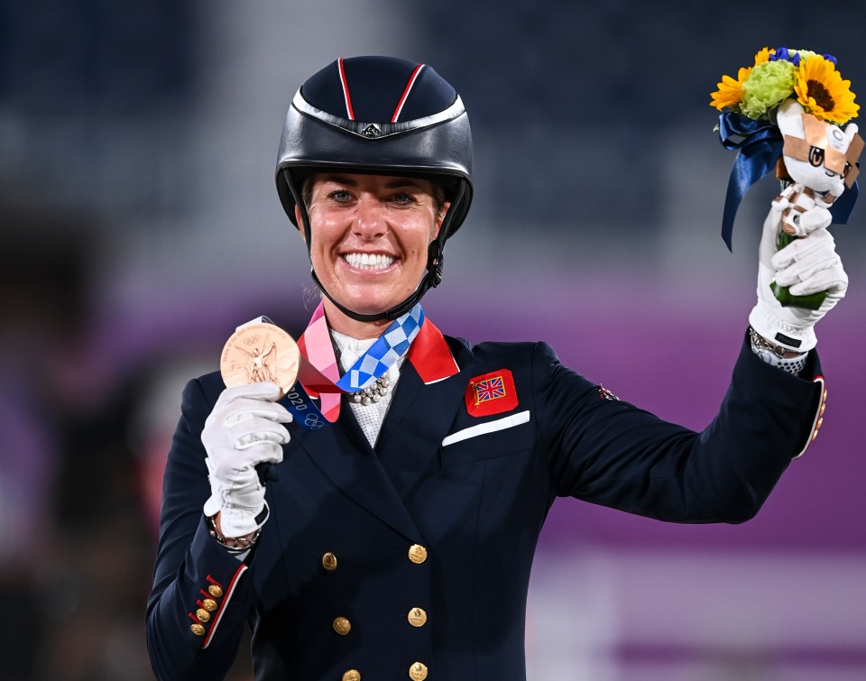 a woman in a military uniform is holding a medal and flowers