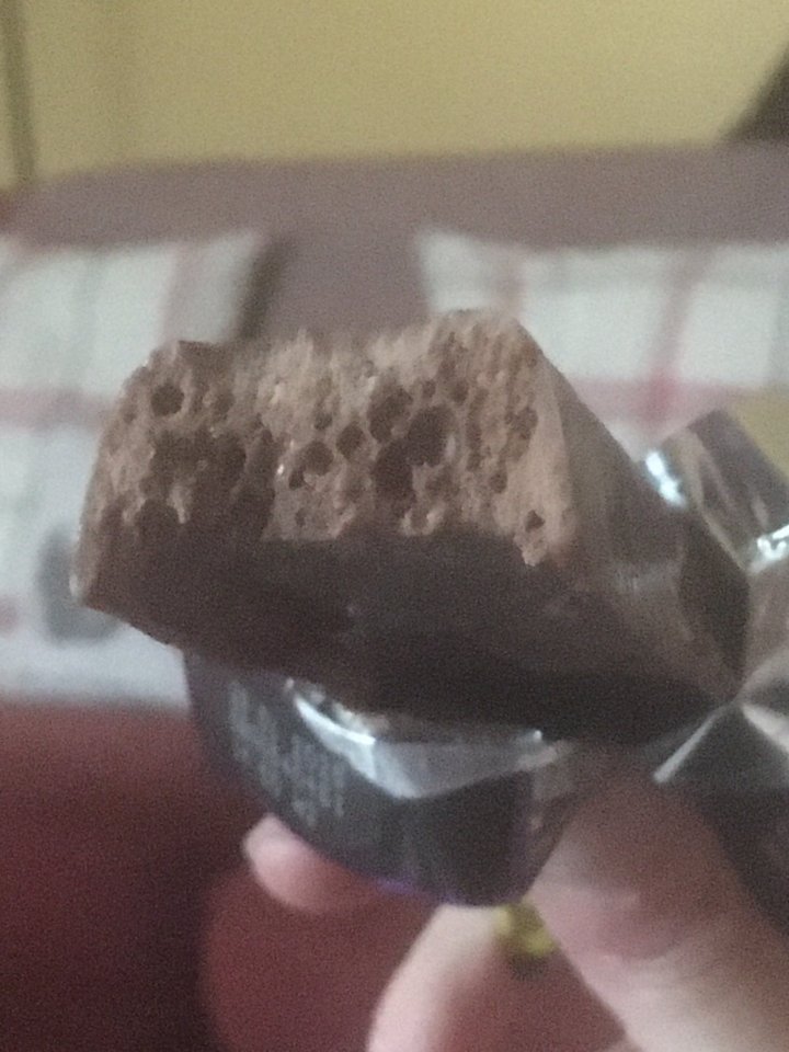 a person is holding a chocolate bar with a bite taken out of it