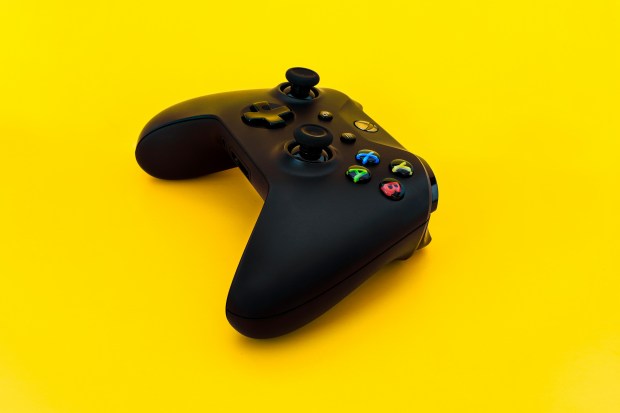 a black video game controller on a yellow background