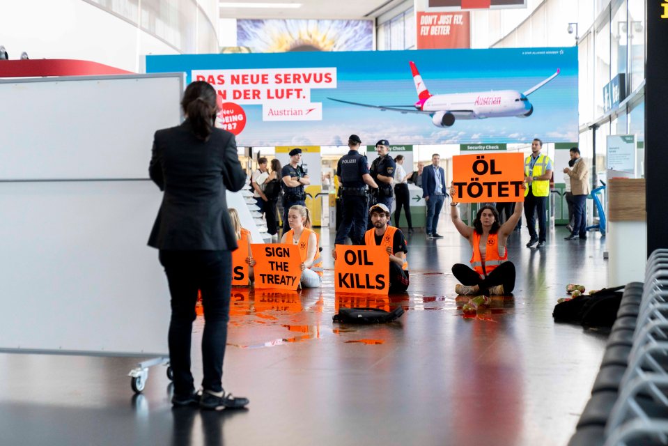 At Vienna airport, Last Generation Austria spilled orange paint and held signs reading 'Oil kills'