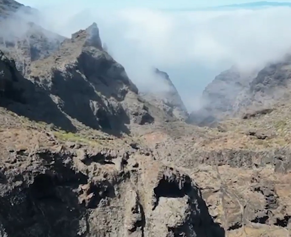 a valley with mountains and clouds in the background