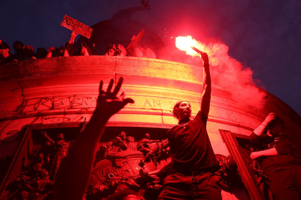 A demonstrator waves a smoke bomb in Paris