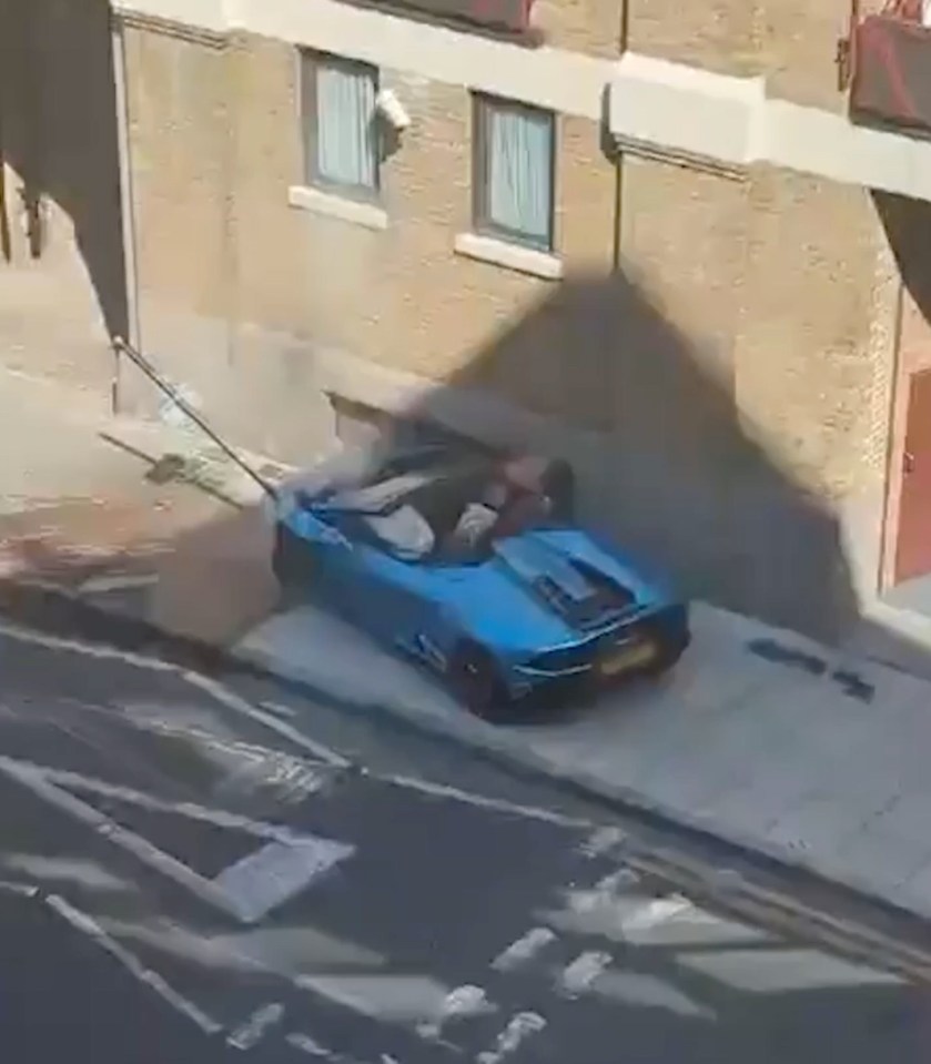 The man appears to be rummaging inside the wrecked supercar