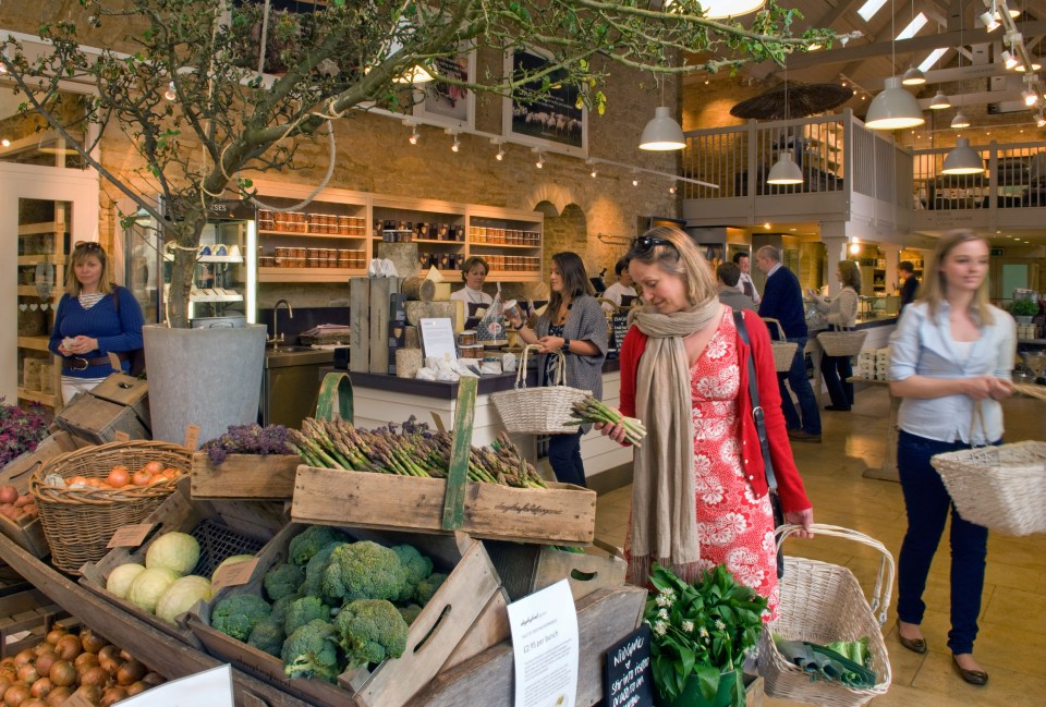 a woman in a red dress is looking at broccoli in a store