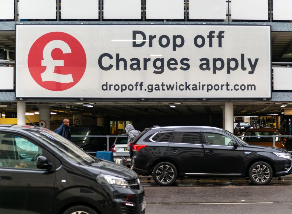 cars are parked under a sign that says drop off charges apply