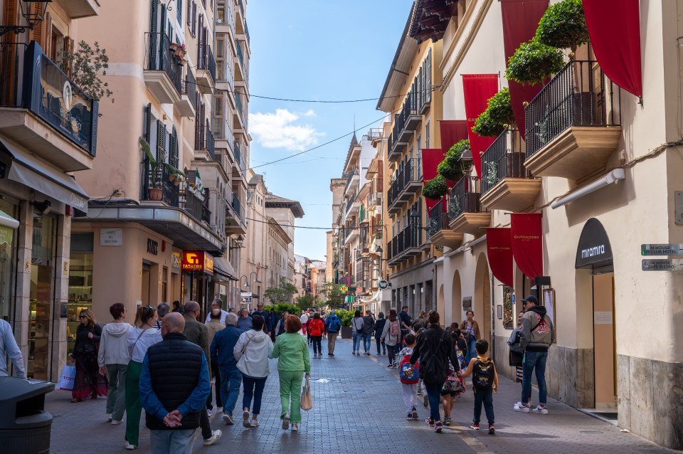 PALMA DE MALLORCA, SPAIN - APRIL 19: People walk past shops including the Cappuccino Grand Cafe and residential apartments along the Carrer de Sant Miquel on April 19, 2024 in Palma de Mallorca, Spain. (Photo by John Keeble/Getty Images)