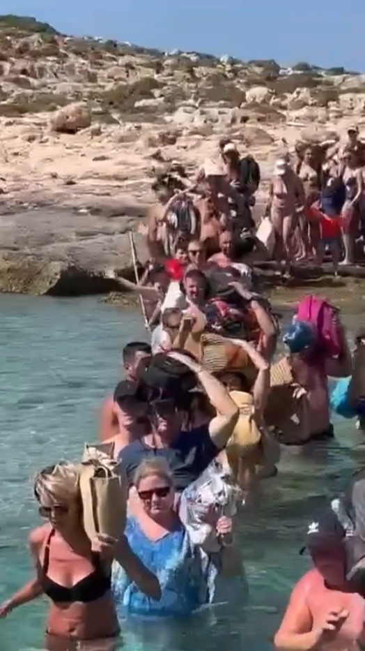 A video showed the holidaymakers trying to keep their belongings dry as they waded through the water