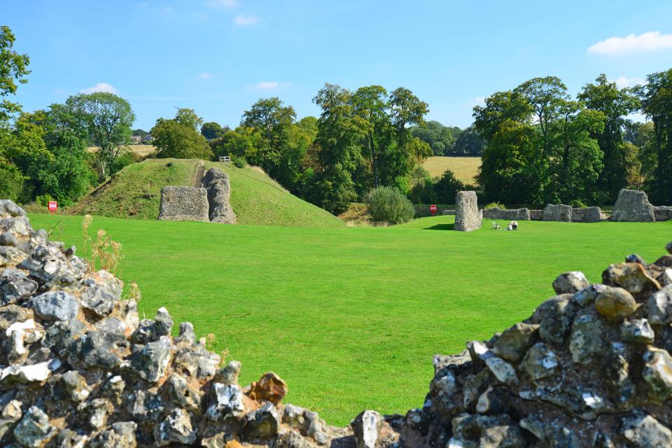 a large grassy field with a stone wall in the foreground