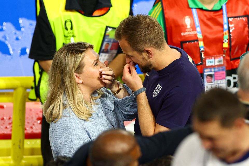 a man in a blue shirt with the word england on it kisses a woman on the cheek