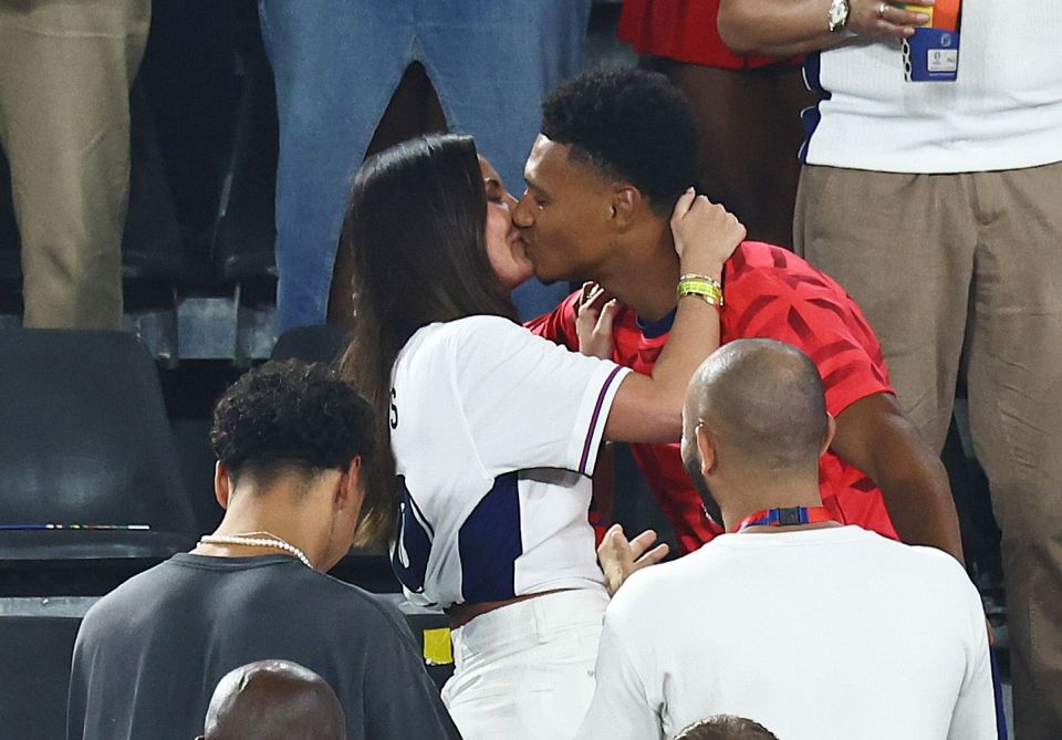 a man in a red shirt is kissing a woman in a white shirt