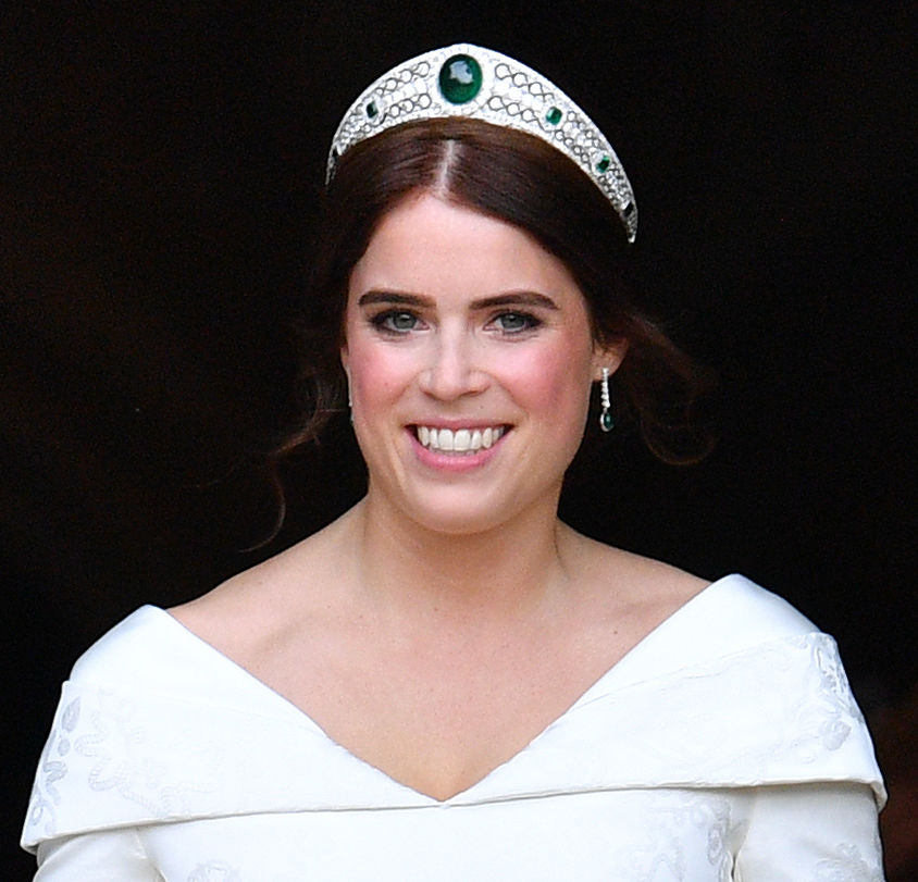 a woman wearing a tiara and earrings smiles for the camera