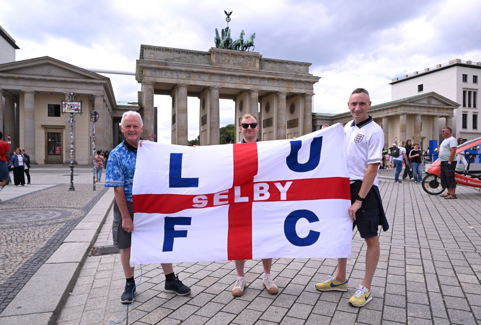 England football fans with a St George flag pose for a picture at the Brandenburg Gate