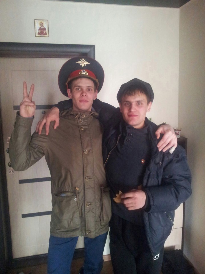 two men posing for a picture with one wearing a military hat