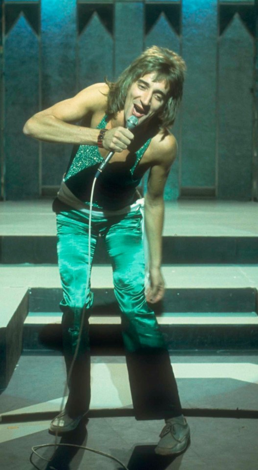 a man singing into a microphone while wearing green pants