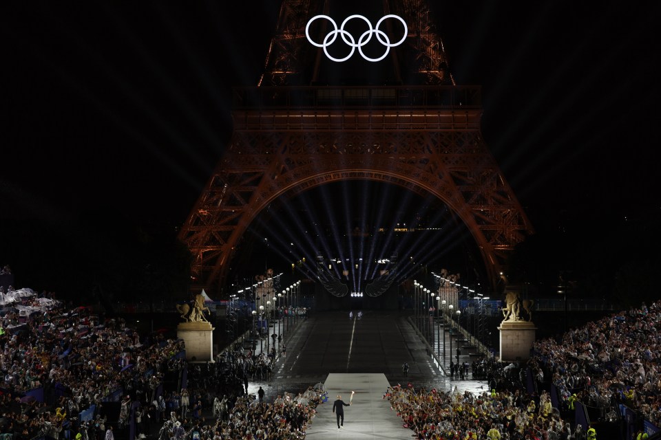 the olympic rings are lit up in front of the eiffel tower