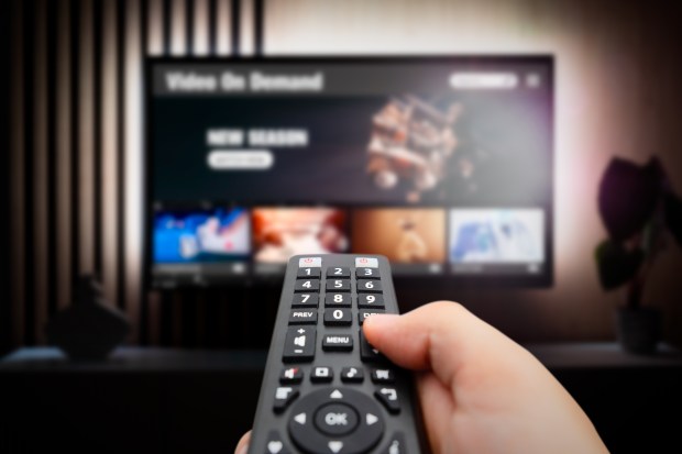 a person is holding a remote control in front of a tv screen that says video on demand