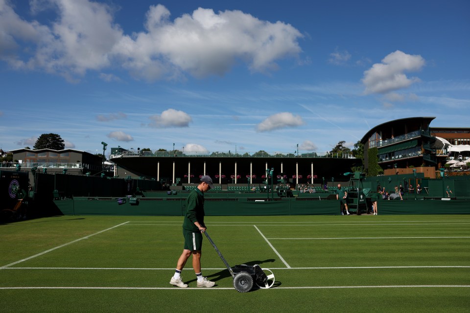 a man pushes a wheelbarrow on a tennis court