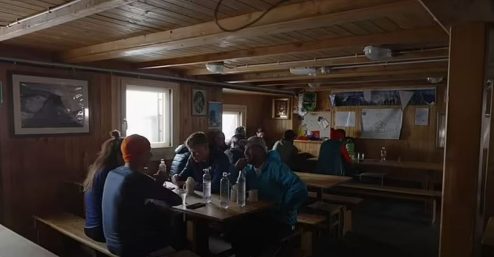 a group of people are sitting at tables in a wooden room