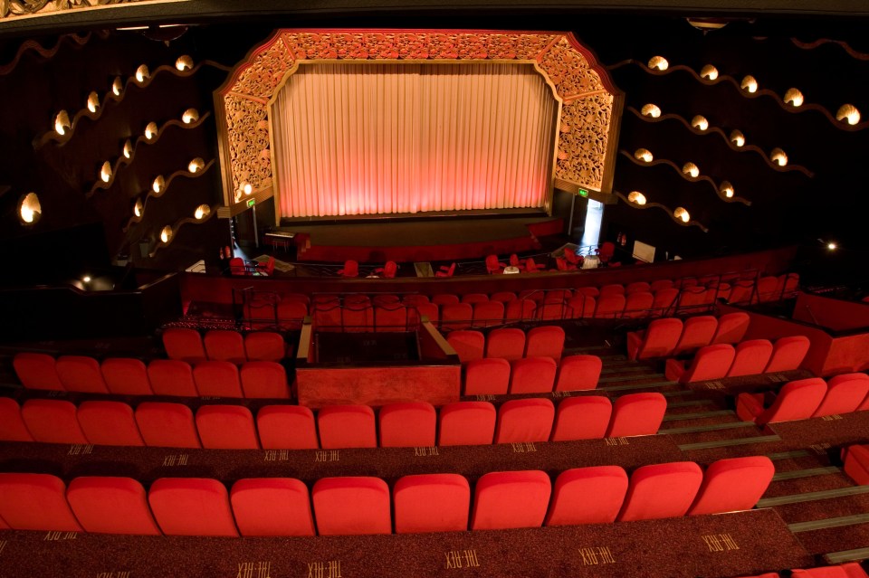 an empty auditorium with red seats and a red curtain