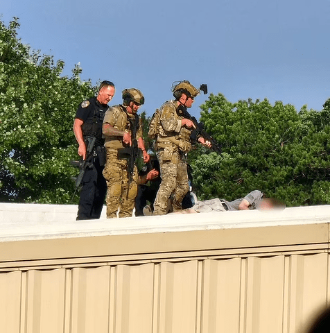 Cops stand over the shooter's body after the attack