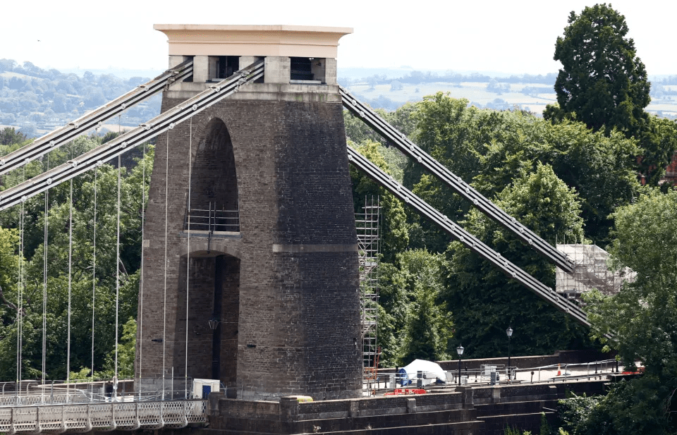 a bridge with a tower on top of it surrounded by trees