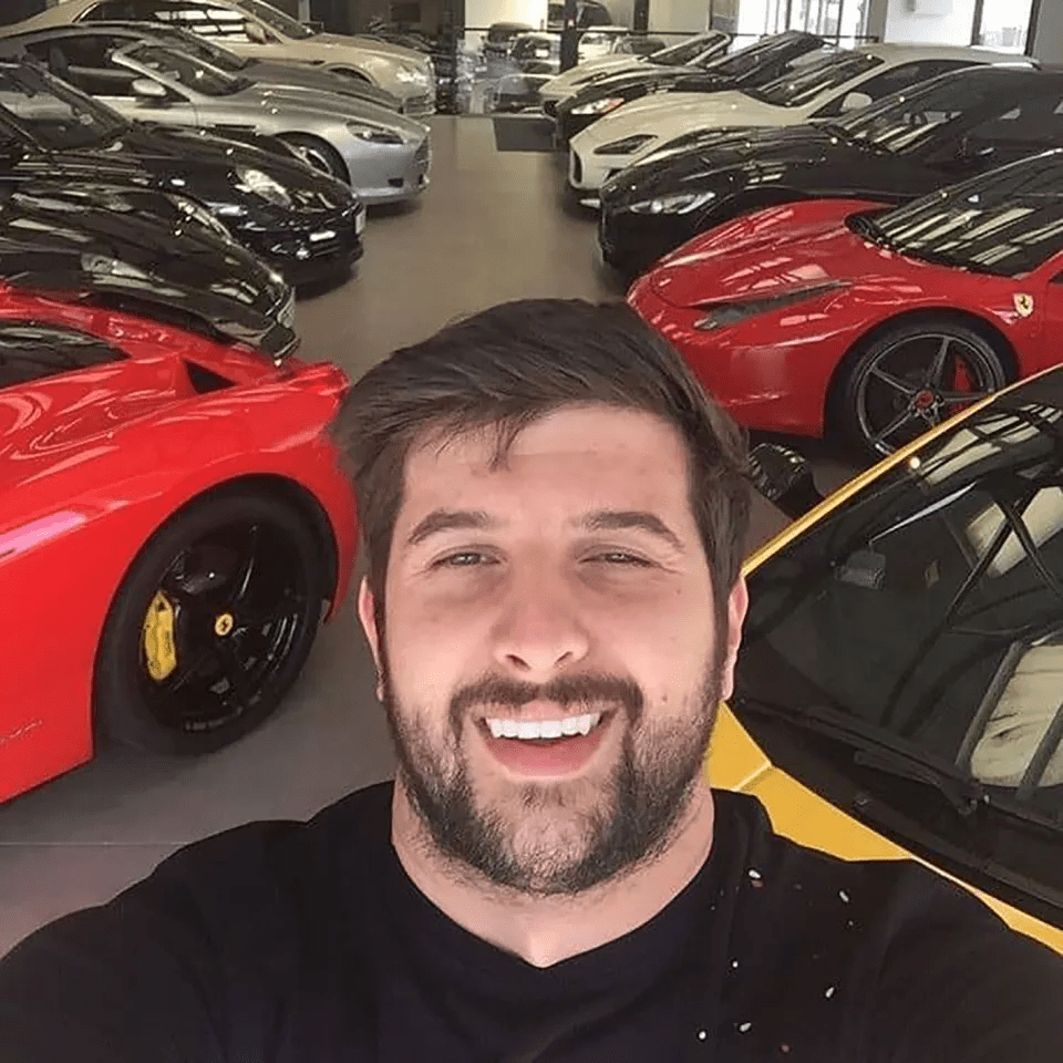 a man taking a selfie in front of a row of cars