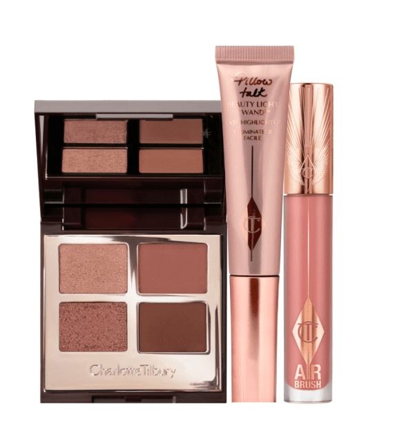 Charlotte Tilbury eyeshadow palette, highlighter wand, and lip gloss.