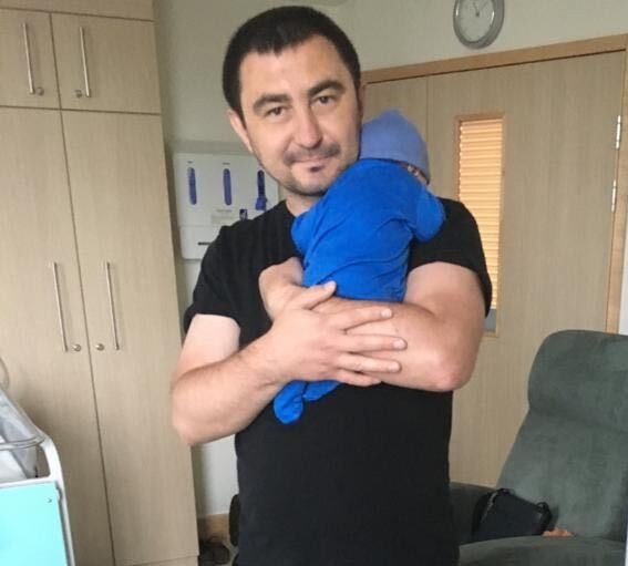 a man is holding a baby in his arms in a hospital room .