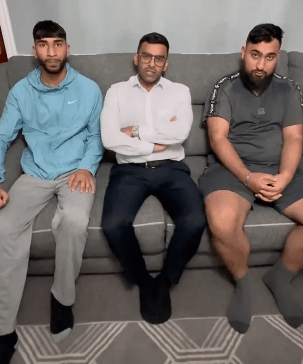 three men are sitting on a couch with their arms crossed