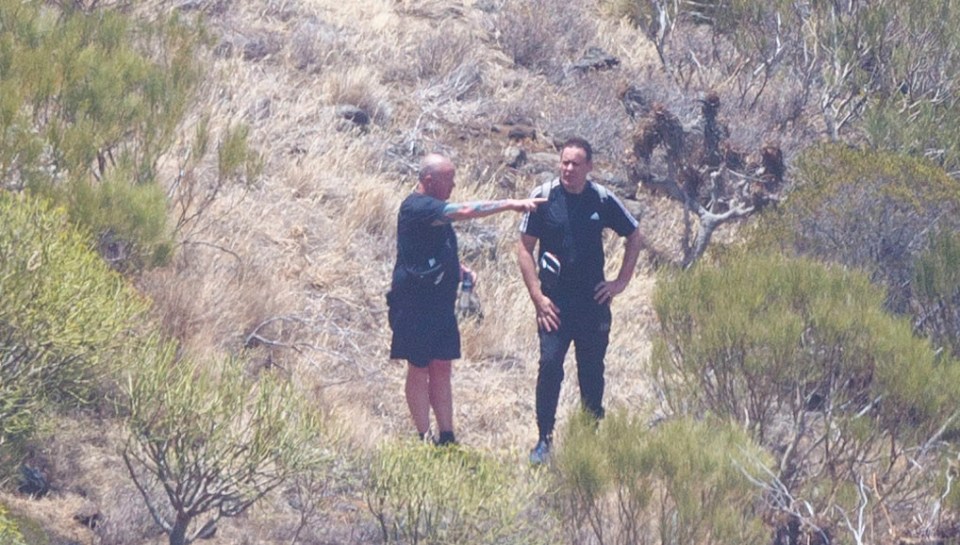 a man in a black adidas shirt stands next to another man