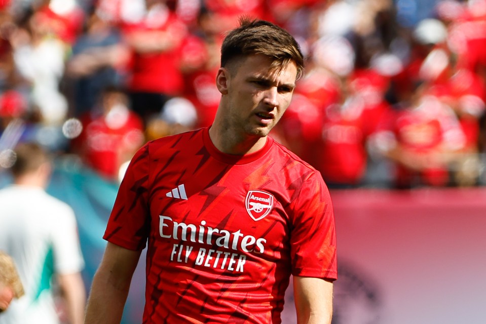 a man wearing a red emirates fly better jersey