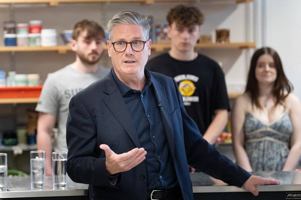 a man in a suit stands in front of a group of people one of whom is wearing a shirt that says sun