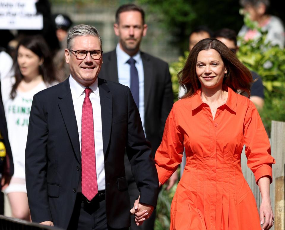 a man in a suit and tie holds hands with a woman in an orange dress