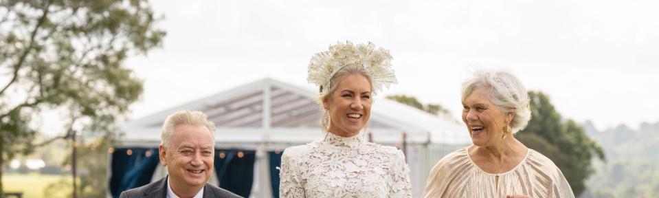 a woman in a wedding dress is walking with her parents