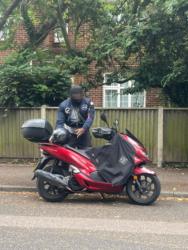 The alleged knifeman, wearing a NASA jacket and a ski mask, pictured behind a motorcycle at the scene