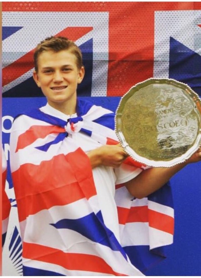 a young man holding a trophy in front of a british flag