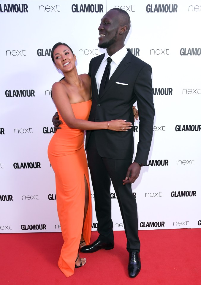 a man and woman pose on a red carpet that says glamour