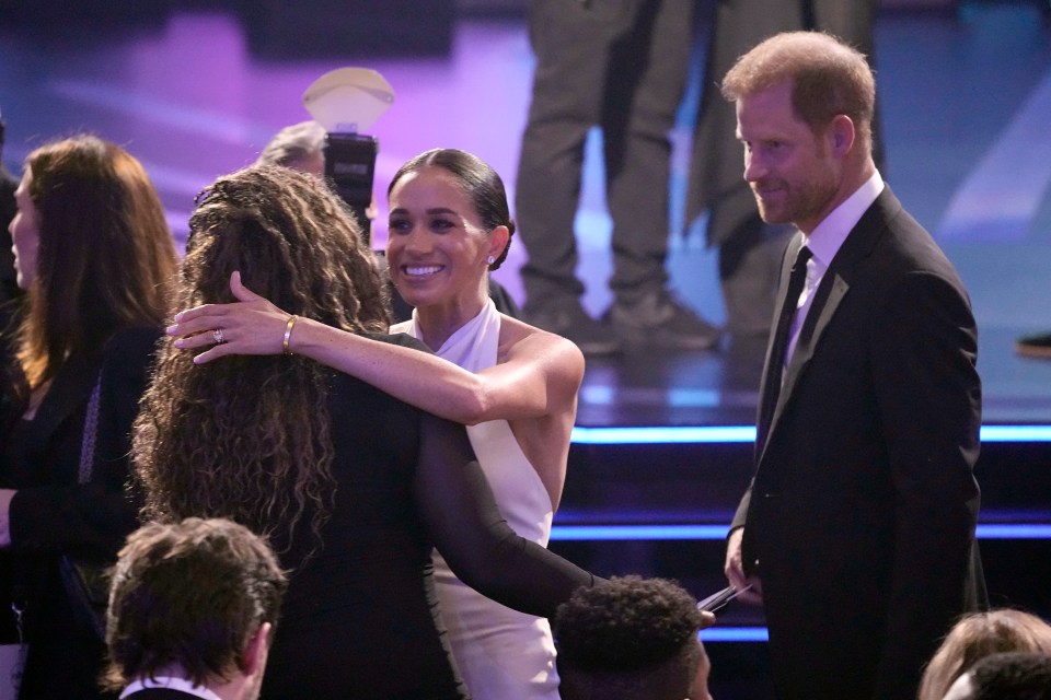 a woman in a white dress is hugging a man in a black suit