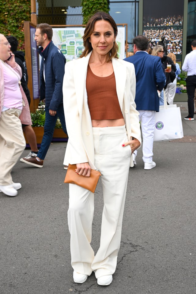 a woman in a white suit stands in front of a sign that says wimbledon