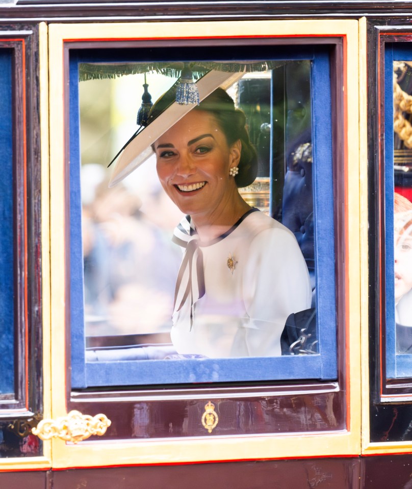 a woman wearing a hat is smiling and looking out of a window